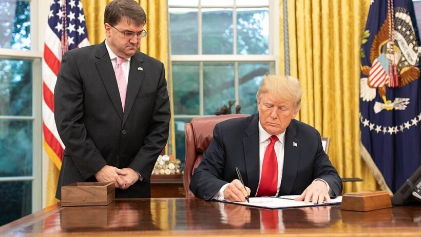 Robert Wilkie watching Donald Trump sign a bill.