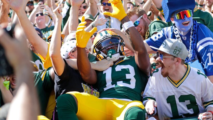Dontayvion Wicks doing a Lambeau Leap after scoring a touchdown