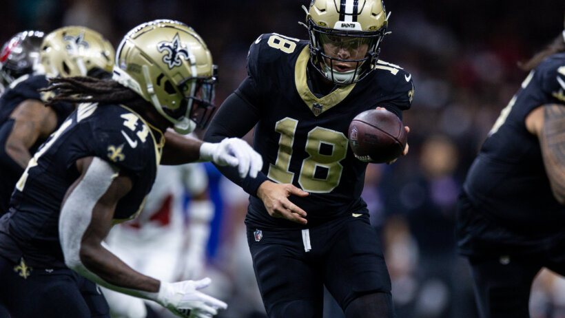 New Orleans Saints quarterback Spencer Rattler hands the ball off to running back Alvin Kamara