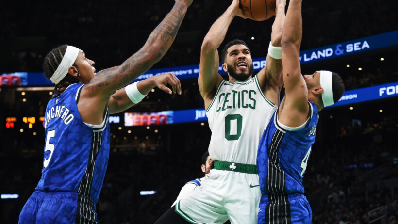 Boston Celtics forward Jayson Tatum drives to the hoop against two Orlando Magic defenders