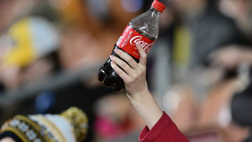 Close-up of a hand holding a bottle of Coke