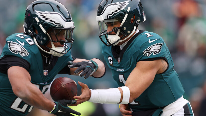 Philadelphia Eagles quarterback Jalen Hurts handing the ball off to running back Saquon Barkley