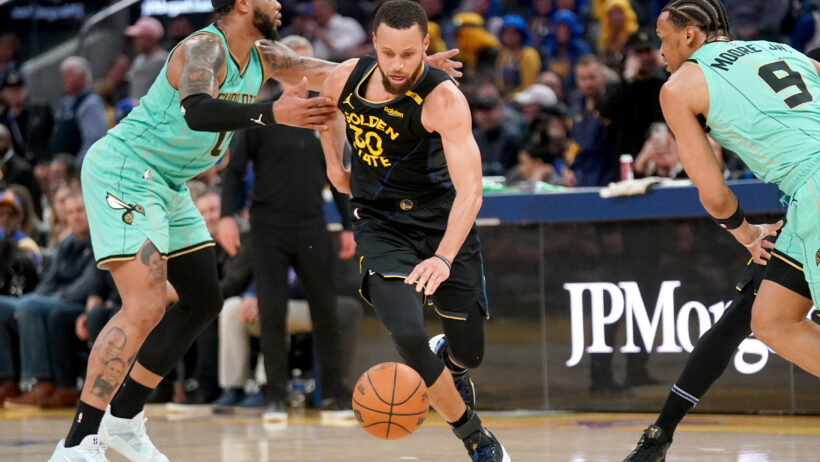 Golden State Warriors guard Stephen Curry dribbles between to Charlotte Hornets defenders