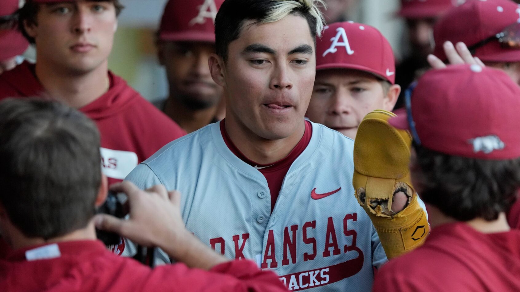 Wehiwa Aloy celebrates in the Arkansas dugout with his teammates.