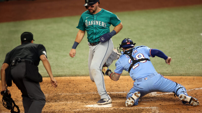 Texas Rangers catcher Jonah Heim tags out Seattle Mariners designated hitter Cal Raleigh at home plate