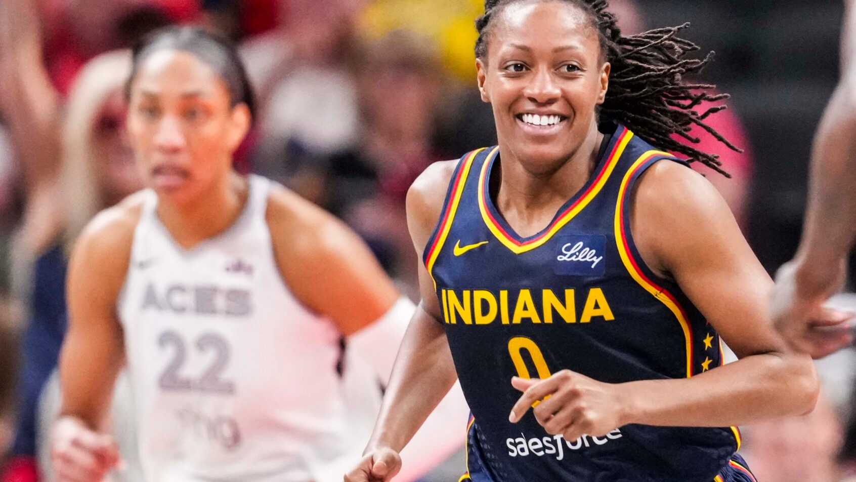 Indiana Fever guard Kelsey Mitchell smiles while running up the court against the Las Vegas Aces