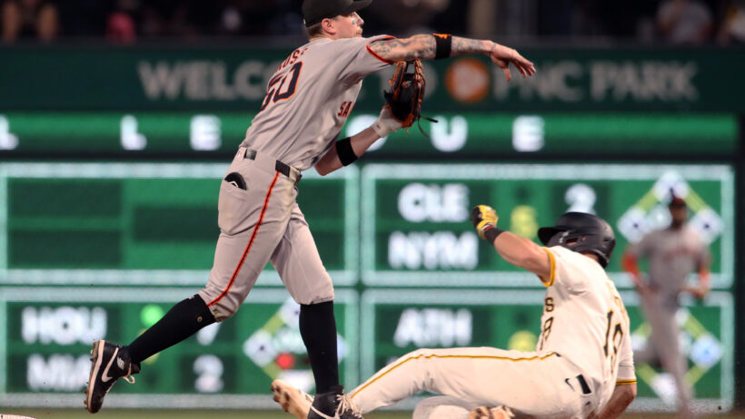 San Francisco Giants second baseman Christian Koss turns a double play as Pittsburgh Pirates shortstop Jared Triolo slides into second