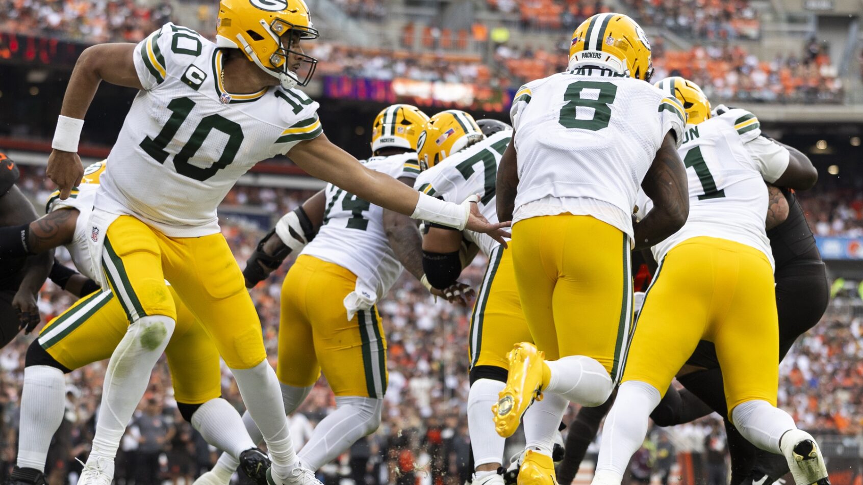 BET99 promo code for NFL Week 4. Jordan Love handing off to Josh Jacobs.