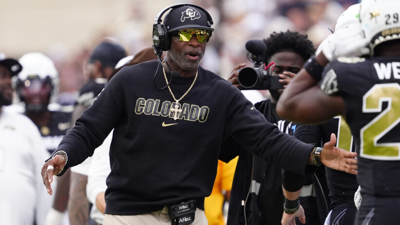 Deion Sanders congratulates his Colorado players on the sideline.