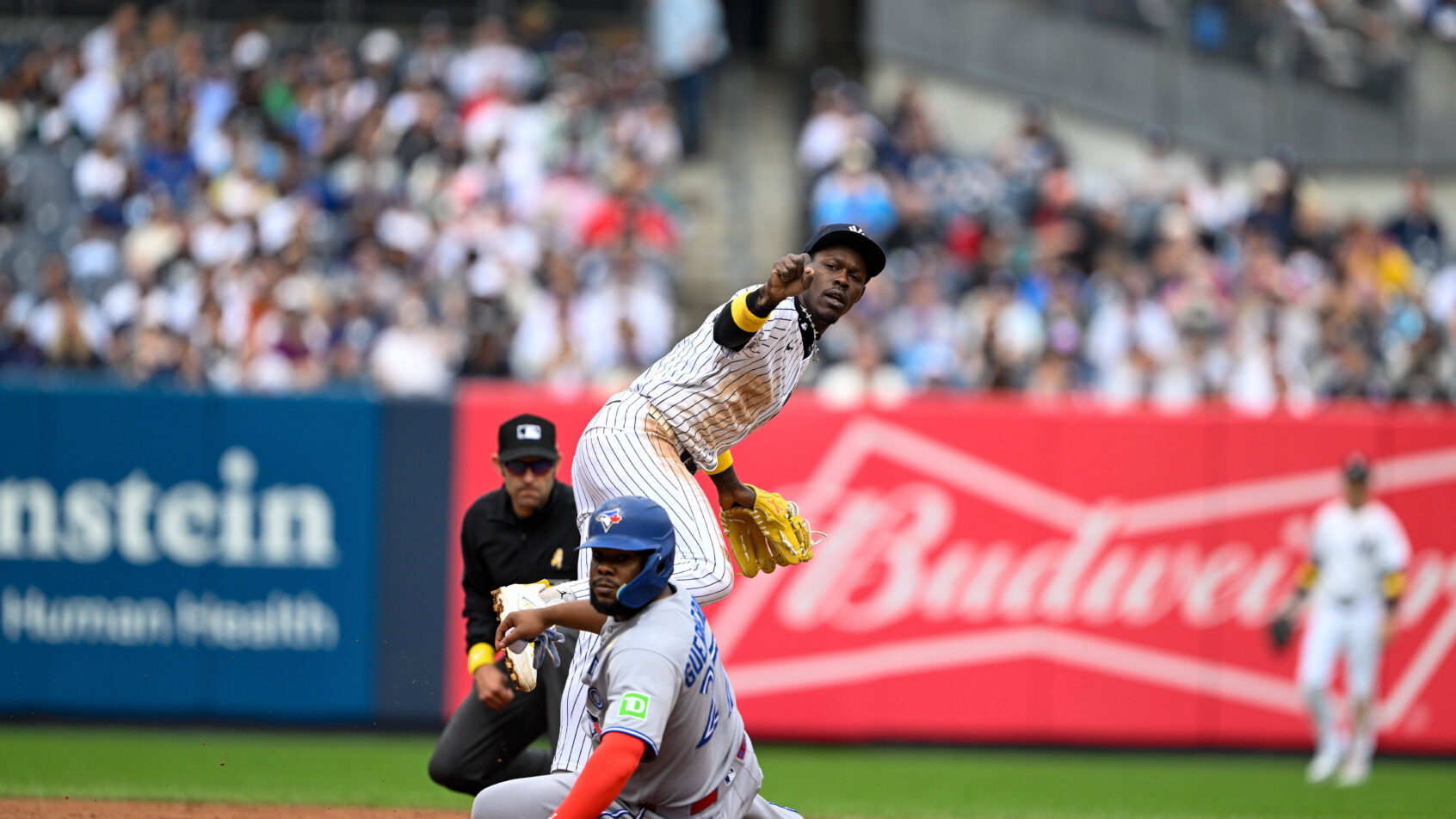 New York Yankees second baseman Jazz Chisholm Jr throws to first as Vlad Guerrero Jr slides into second