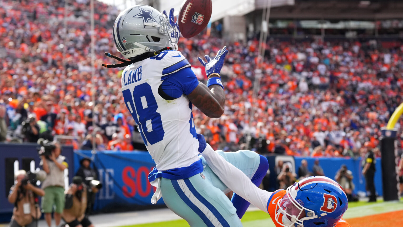 CeeDee Lamb juggles a catch in a game versus the Broncos.