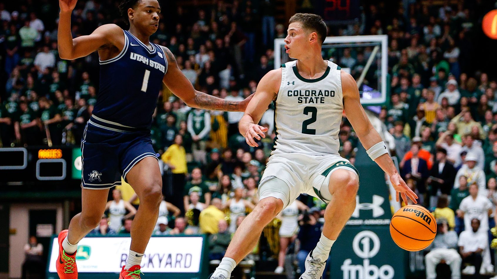 Colorado State Rams guard Brandon Rechsteiner dribbles the ball against a Utah State defender.