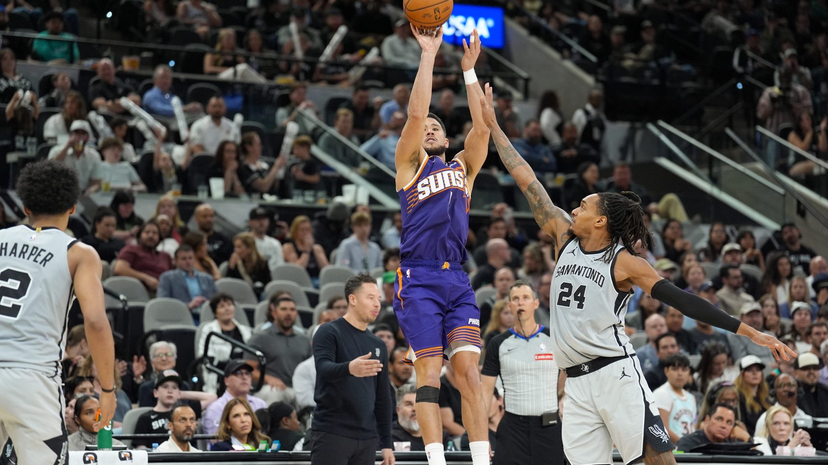 Devin Booker shoots in front of San Antonio Spurs guard Devin Vassell.