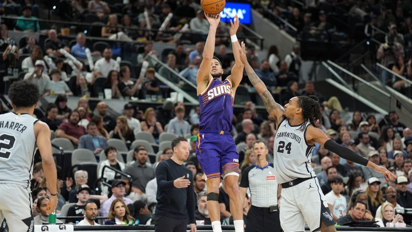 Devin Booker shoots in front of San Antonio Spurs guard Devin Vassell.