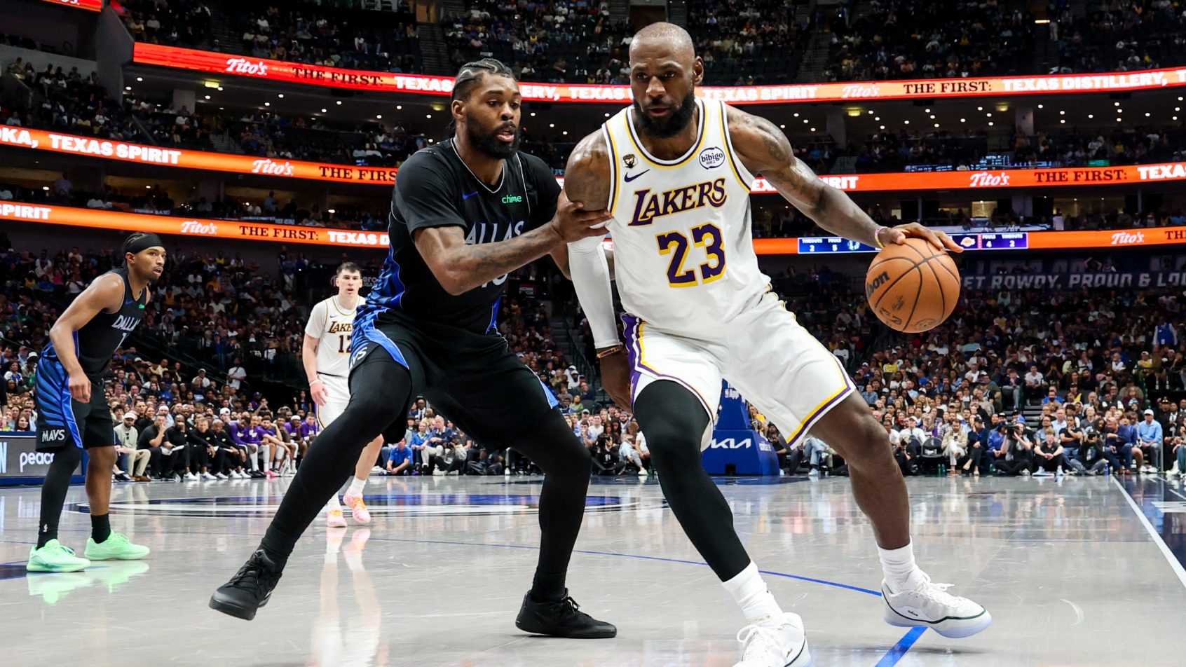 Los Angeles Lakers forward LeBron James controls the ball as Dallas Mavericks forward Naji Marshall defends.