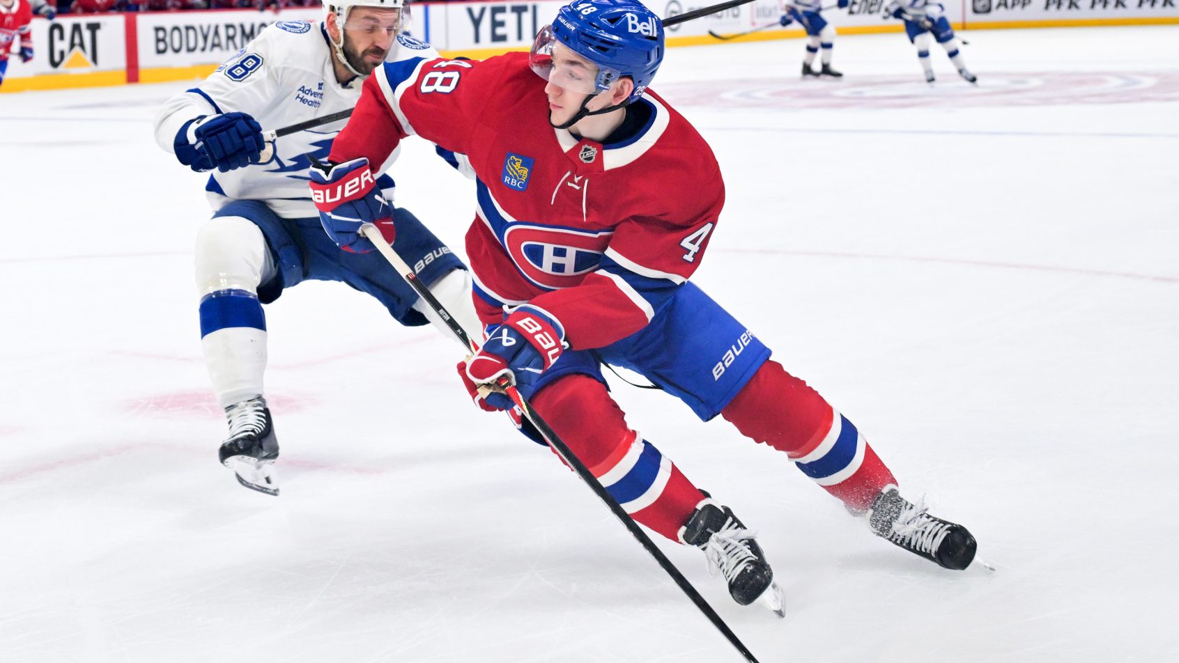 Lane Hutson controls the puck in his own end with a Lightning forechecker right on him.