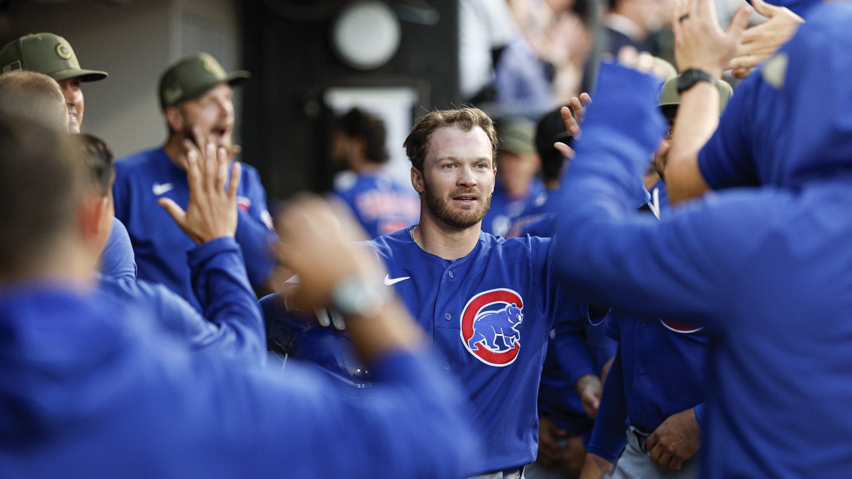 Ian Happ celebrates with his teammates in the Cubs dugout.