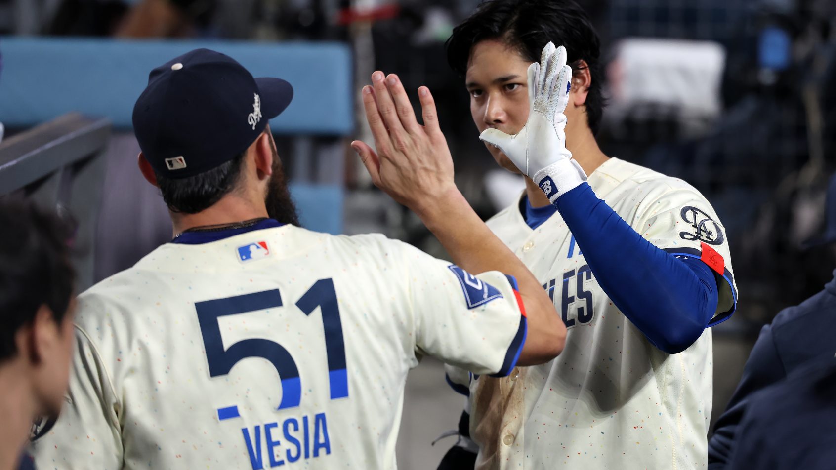 Shohei Ohtani gets a high-five in the dugout from a Dodgers teammate.