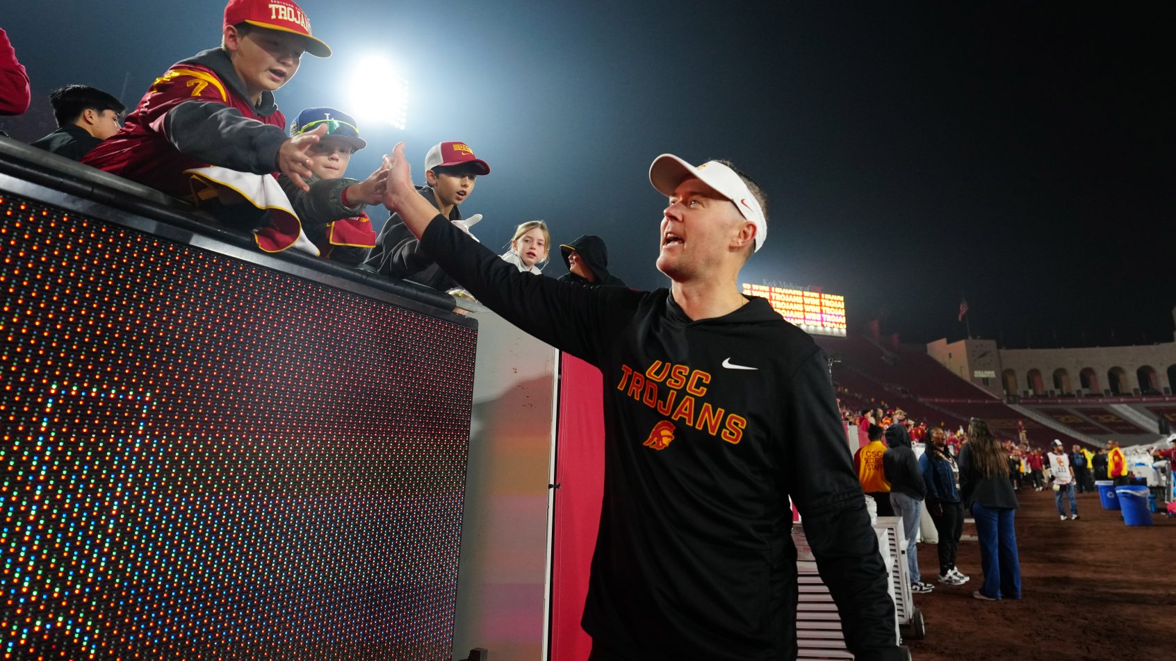 Lincoln Riley high-fives with fans after a USC win.