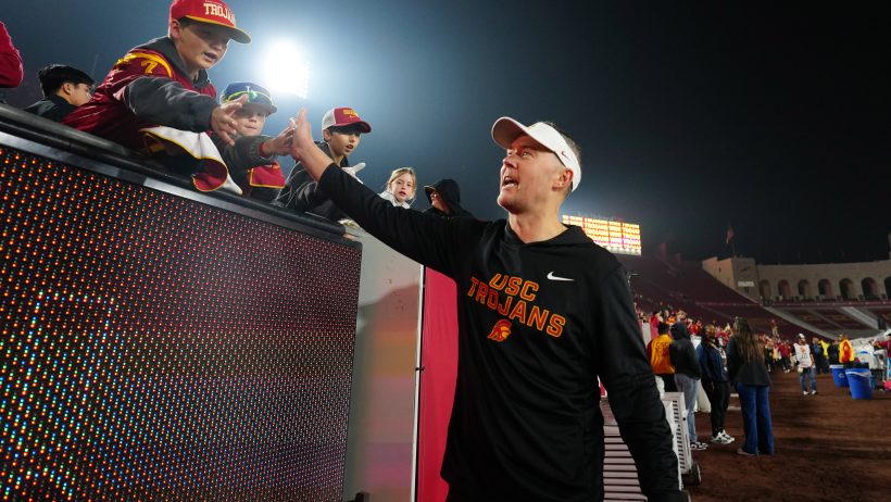 Lincoln Riley high-fives with fans after a USC win.