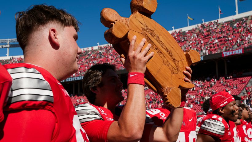Ohio State quarterback Julian Sayin hoists the Illibuck trophy after beating Illinois