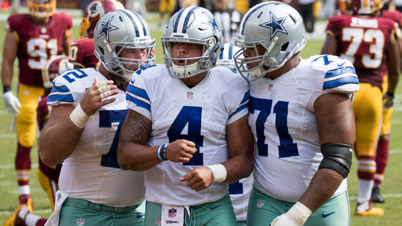 Dak Prescott celebrating with his offensive linemen after scoring a TD