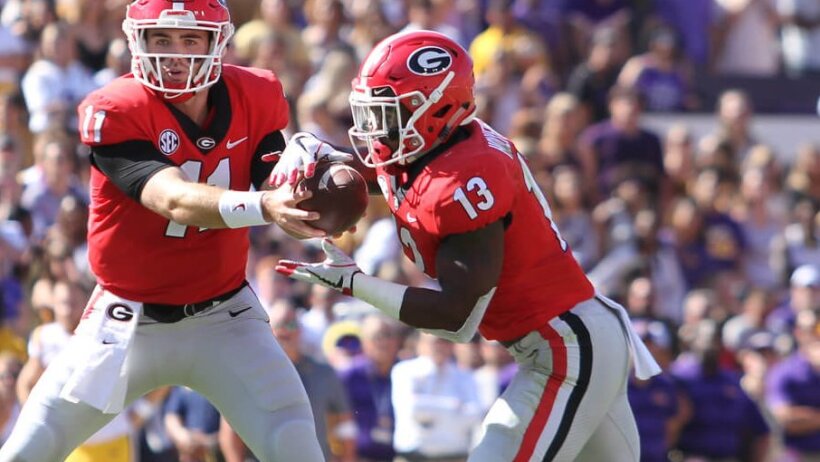 Georgia Bulldogs quarterback Jake Fromm hands the ball off to running back Elijah Holyfield