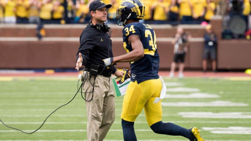 Jim Harbaugh high fiving one of his Michigan players.