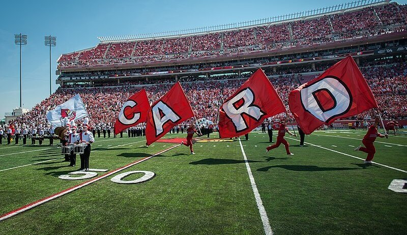 Louisville Cardinals cheerleaders running across the field.