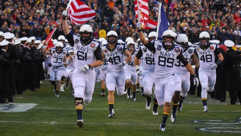 Navy football team running onto the field