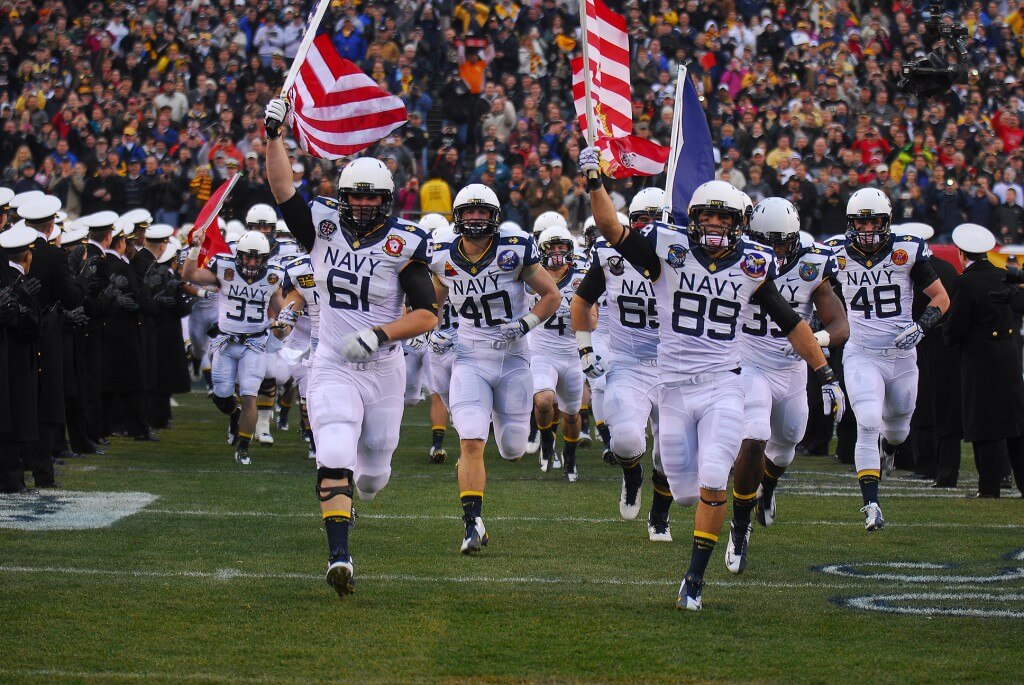 Navy football team running onto the field