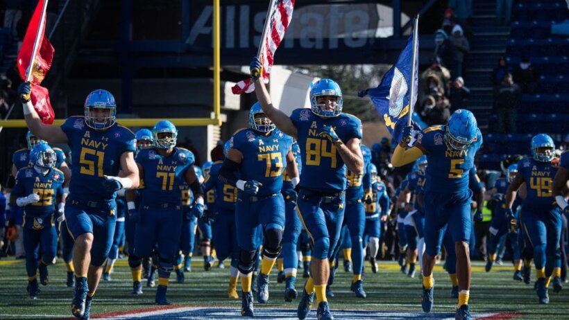 Navy football team running onto the field