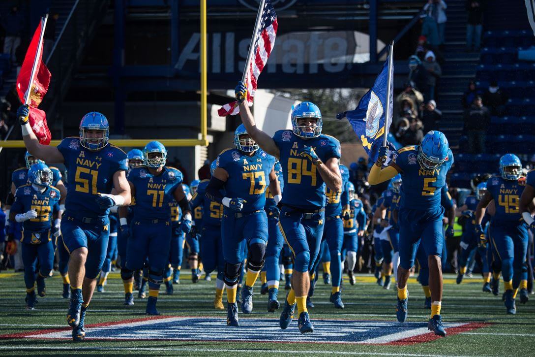 Navy football team running onto the field