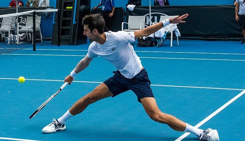 Novak Djokovic stretches to hit a backhand.