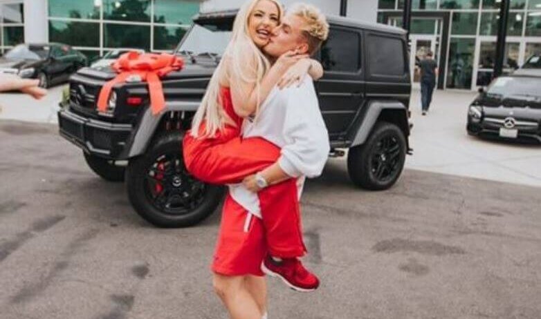 Tana Mongeau and Jake Paul hugging outside a Mercedes-Benz dealership.