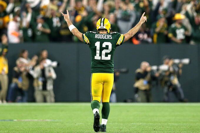 Aaron Rodgers with his arms in the air celebrating