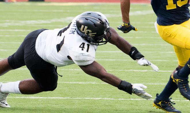 A UCF defender dives at the feet of a Michigan ball carrier