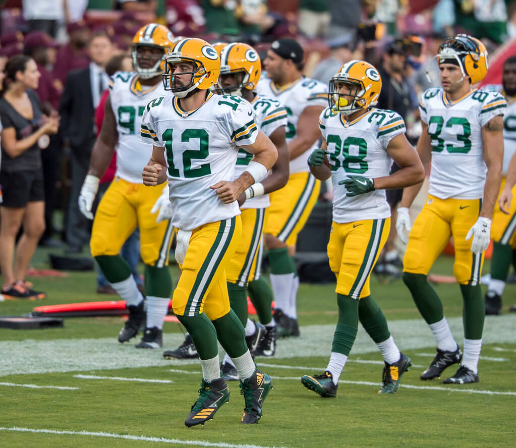 Aaron Rodgers and the Green Bay Packers run onto the field.