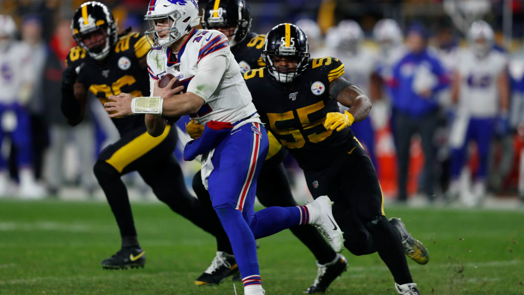 Buffalo Bills quarterback Josh Allen running with the ball and Pittsburgh Steelers linebacker Devin Bush pursuing him.