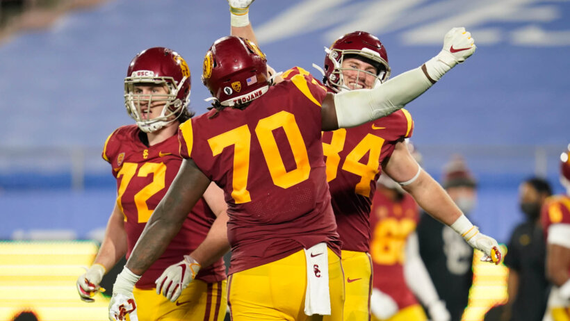 University of Southern California offensive linemen Andrew Vorhees, Jalen McKenzie, and tight end Erik Krommenhoek celebrating a touchdown.