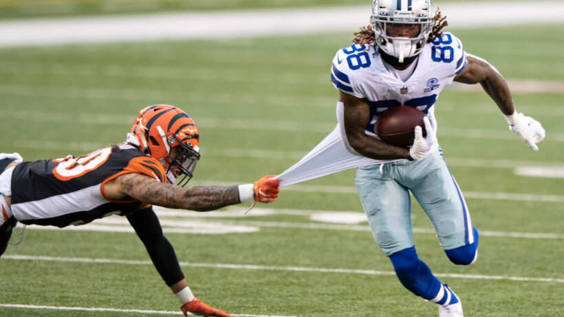 CeeDee Lamb running with football while jersey is grabbed