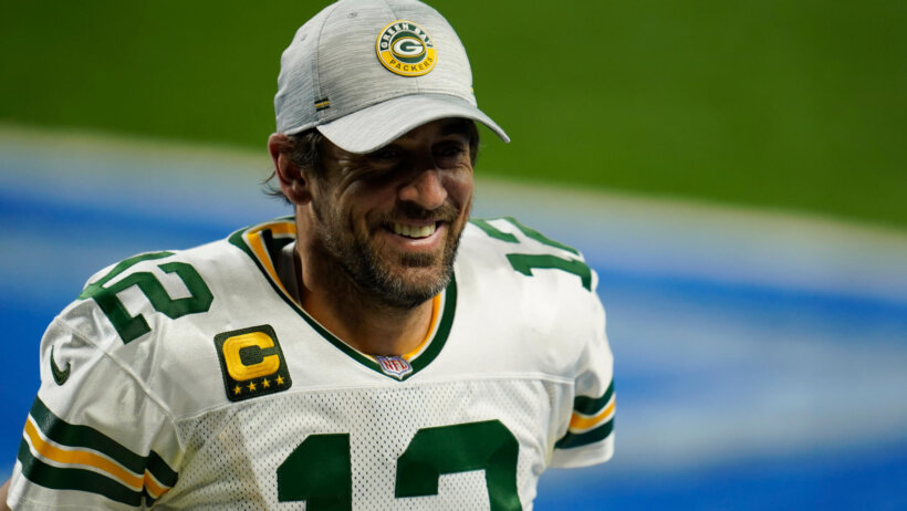 Green Bay Packers quarterback Aaron Rodgers smiling as he walks off the field.