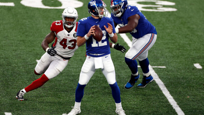 Colt McCoy standing in pocket preparing to throw as defender gets close to hitting him