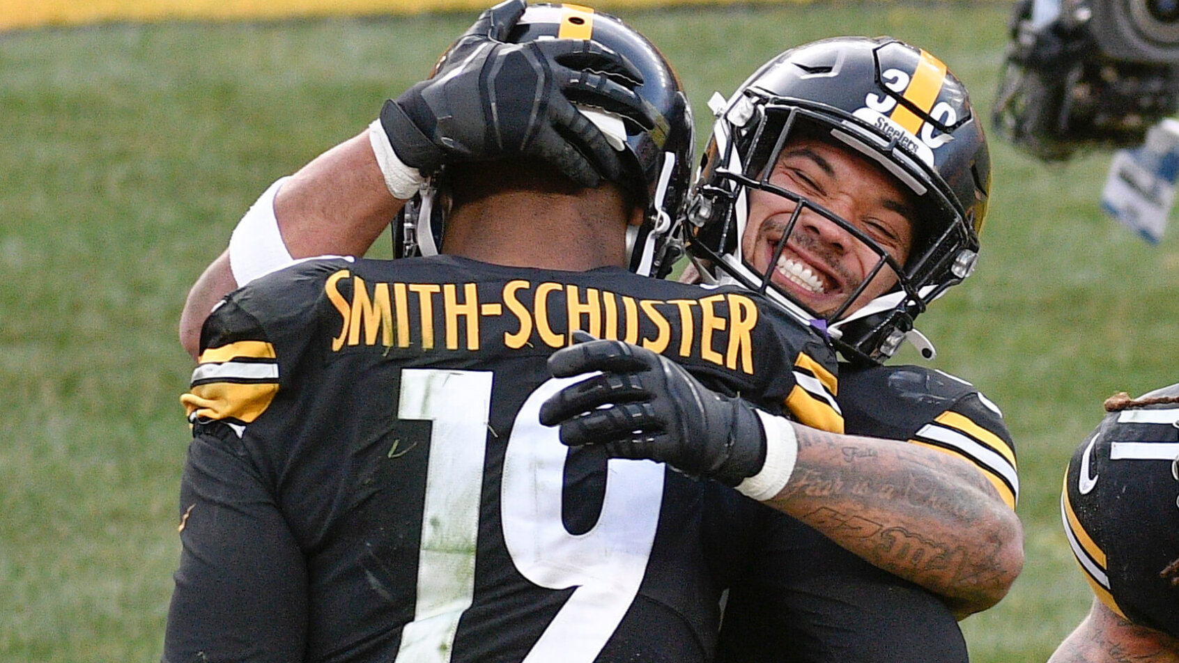 Pittsburgh Steelers wide receiver JuJu Smith-Schuster celebrating on the field by giving running back James Conner a hug.