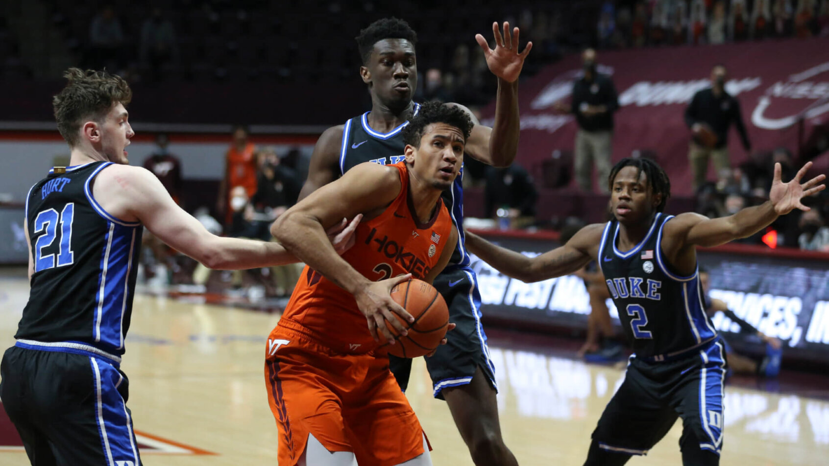 Keve Aluma with basketball in the paint surrounded by three defenders