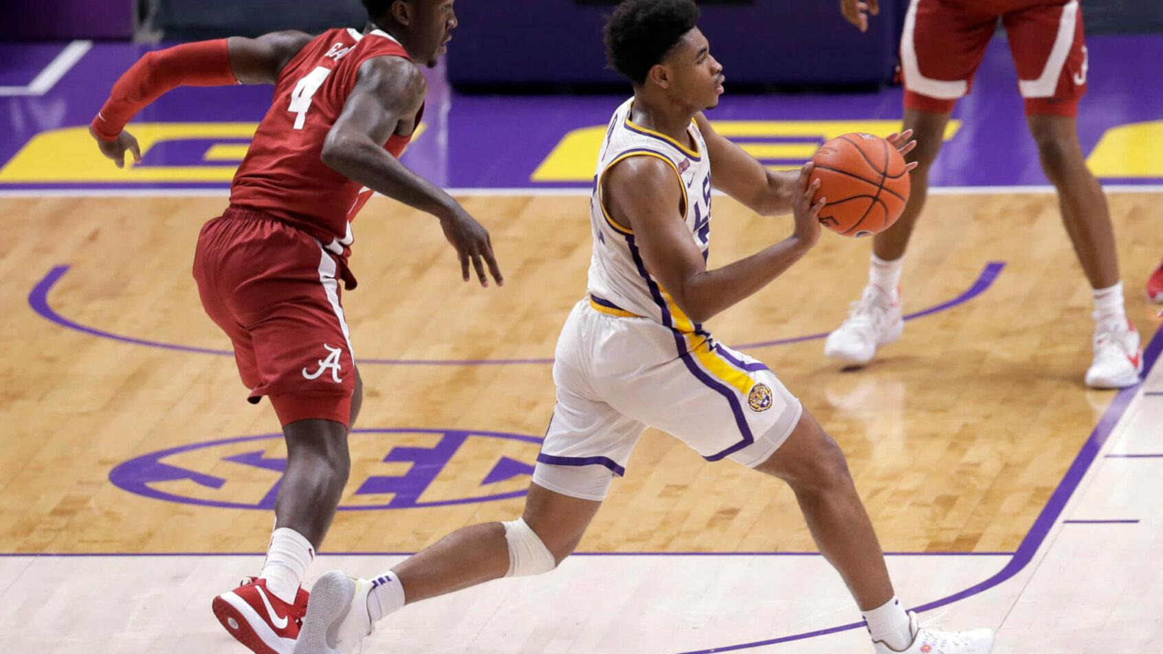 LSU guard Cameron Thomas passing the ball as Alabama forward Juwan Gary defends during a college basketball game.