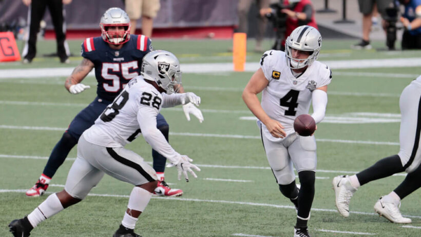 Josh Jacobs and Derek Carr making a play on the field during a game.
