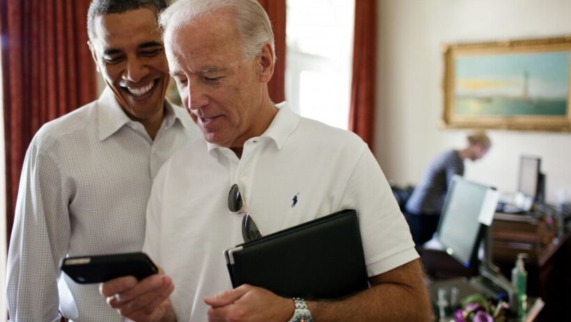 Joe Biden and Barack Obama looking at a smartphone
