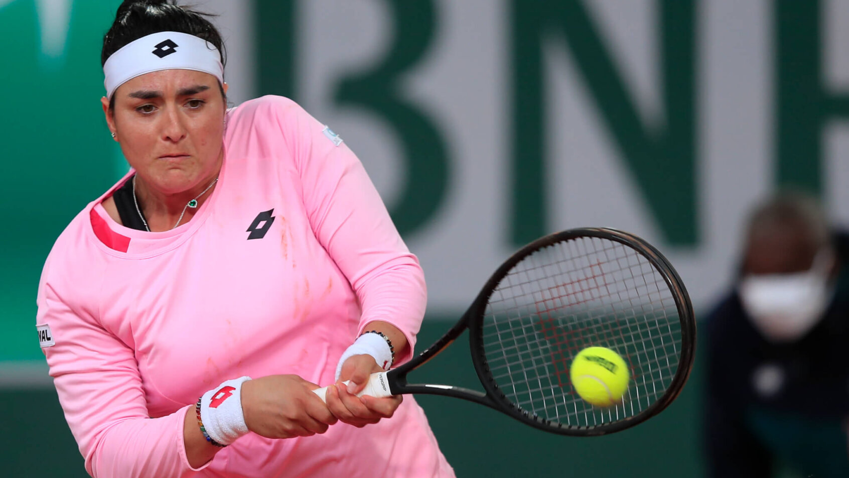 Ons Jabeur hitting a backhand return during a tennis match.