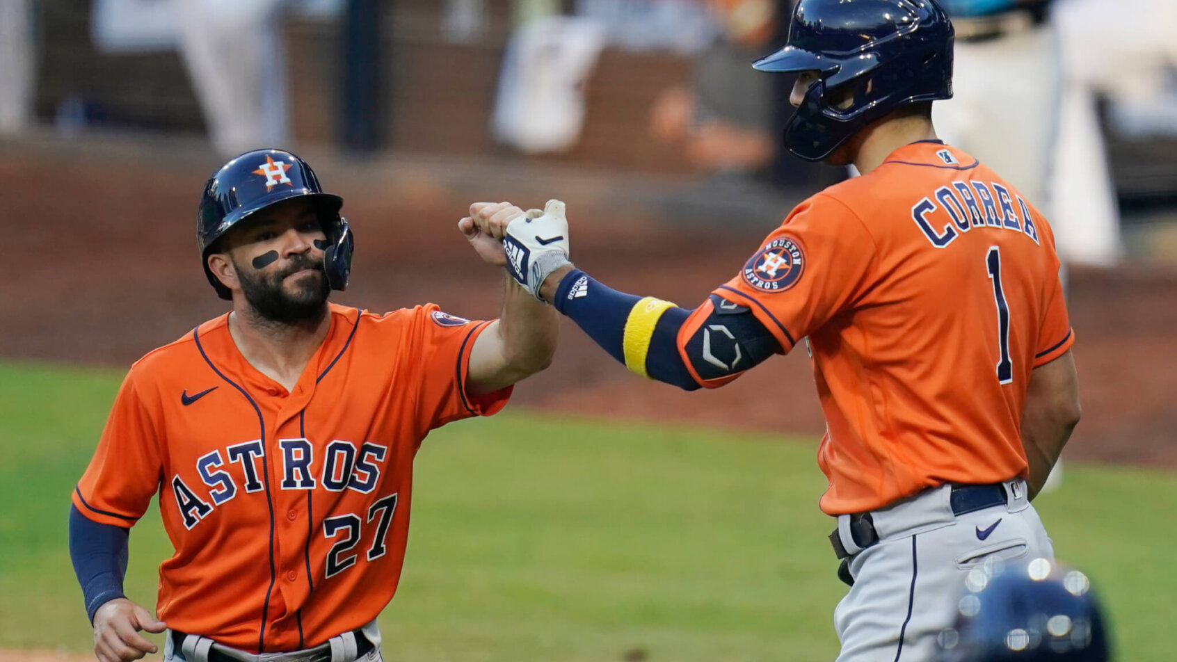 Houston Astros' Jose Altuve and Carlos Correa celebrating on the field after scoring a run.